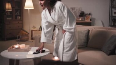 Duştan sonra beyaz bornozlu, rahat ve güzel bir kadının kanepede oturup TV 'yi açtığı rahat oturma odasında mumlar ve tütsü çubuklarıyla dinlendiği bir sahne.