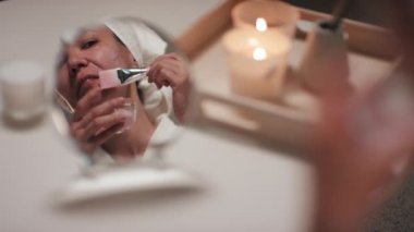 Güzel görünümlü orta yaşlı bir kadının aynanın karşısında yüzüne jöle maske takarak aynaya bakarken akşamları mum ve tütsü çubuklarının yanında durduğunu gördüm.