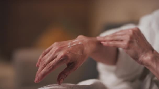 保湿効果のある柔らかく滑らかなクリームで選択的に焦点を当てた認知できない中年女性の手のクローズアップ — ストック動画