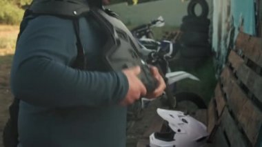 Motosiklete binmeden önce göğüs koruyucusu takan bir adamın el bilgisayarı.