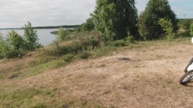 İnsansız hava aracı, göl kenarındaki motosikletlerinin üzerinde oturan ve ormana gittikten sonra sohbet eden adamların görüntülerini çekiyor.