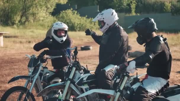 スローモ中出しの陽気な3人の男でギアとヘルメットに座っているオートバイの屋外と拳バンピングお互いに乗る前に行く — ストック動画