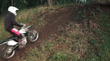 Ormandaki off-road pistinde motorsiklet süren kasklı adamların izini sürüyorum.