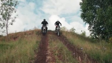 Bulutlu bir günde ormanda motosiklet süren kasklı adamların yavaş çekim görüntüleri.