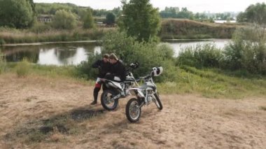 Orman bölgesinde dinlenen ve cep telefonuna bakan iki motosikletlinin robot resmi.
