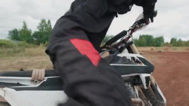Kask takmış, motosiklet sürüp uzaklaşan tanınmamış bir adamın görüntüsü.