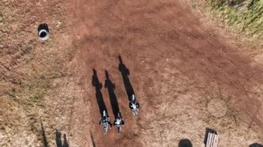 Miğferli adamların off-road pistinde engelli motosiklet sürerken çekilen insansız hava aracı görüntüleri.