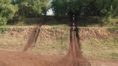 Ormandaki engebeli arazide motorsiklet süren kasklı sporcuların yavaş çekimleri.