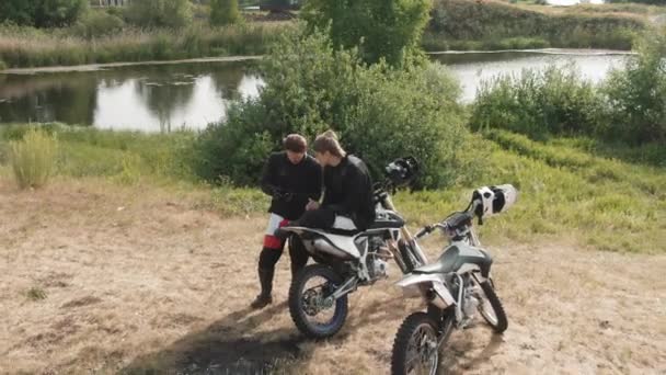 Снимок Беспилотника Молодых Мотоциклистов Отдыхающих Озера Смотрящих Мобильный Телефон — стоковое видео
