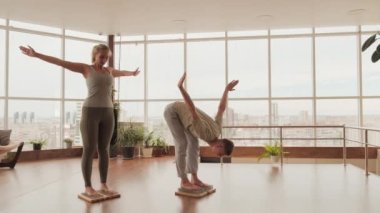 Yoga sınıfındaki beyaz bir çiftin sadhu tahtasında durup nefes alma ve esneme egzersizleri yapması.