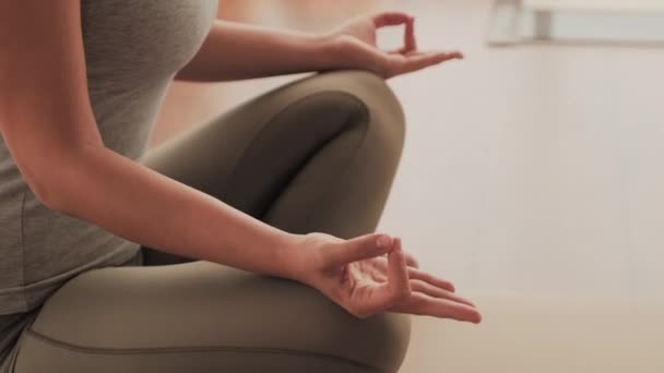 无法辨认的女人坐在瑜伽垫上沉思 双腿交叉 做着特殊的手指姿势 中间段镜头 — 图库视频影像
