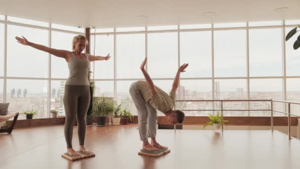 在瑜伽课上 有一对年轻的高加索夫妇站在沙地湖的木板上 练习用钉子站着做呼吸和伸展运动 — 图库视频影像