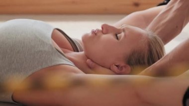 Gözleri kapalı, kolları bağlı, derin derin nefes alan, tanınamaz bir erkek eğitmene yardım eden ve ona destek olan bir kadın.