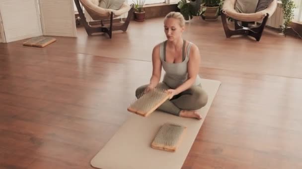 从上面的女性练习瑜伽的镜头中可以看出 当她们坐在瑜伽垫上的时候 她们在练习瑜伽时 会检查重力钉板上是否有钉子 并把手掌放在上面放松 — 图库视频影像