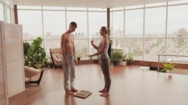 Genç kadın yoga hocası, sadhu-yoga 'nın temel kurallarını anlatıyor. Tırnak tahtasında elini tutmasına yardım ediyor.