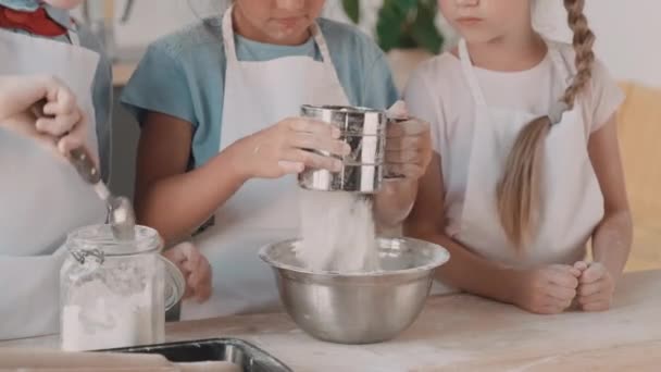 알아볼 수없는 아이가 밀가루를 단지에서 숟가락으로 퍼내어 소녀의 그릇에 수동형으로 — 비디오