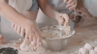 Metalik kasede hamur yoğuran tanınmamış çocukların yakın çekimleri, bir çocuk kaşık çekmeye çalışıyor.