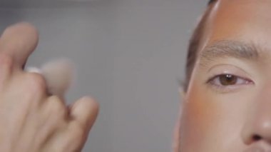 Alnında fırça ve bronzlaştırıcı bronzlaştırıcı kullanarak ve yakışıklı erkek modelin elmacık kemiklerini kullanarak tanınmaz hale gelmiş.