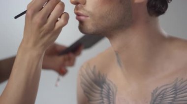 Tanımlanamayan MUA 'yı fırça kullanarak ve yakışıklı genç adama göz farı sürerek yukarı kaldır.