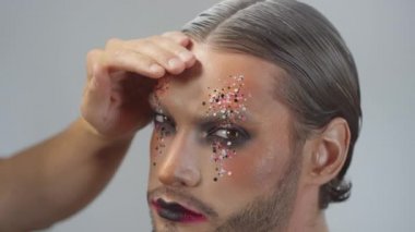 Beyaz renk spreyi ve makyajlı erkek modelin boyalı saçlarını kullanarak tanınmaz hale getirilmiş MUA 'nın el kamerası.
