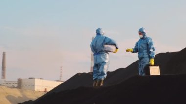 Koruyucu üniformalı ekoloji uzmanlarının tam karesi çalışan fabrikalar, kirlenmiş toprak ve her yerde bol miktarda duman bulunan sanayi bölgesini ziyaret ediyorlar.
