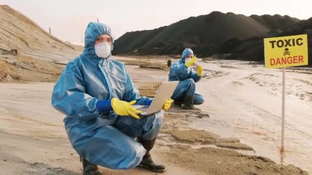 某危险工业城市两名身穿防护服的生态学家对污染水进行质量控制试验的全景画像 — 图库视频影像