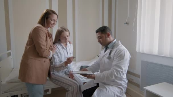在中东男性医生给她的知情同意文件上 坐在病床上的正在康复的女病人中的一张照片 — 图库视频影像