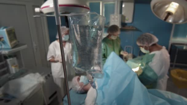 プロの外科医と明るい手術室でナルコシスの下で点滴で男性患者を操作彼のアシスタントを示す作業プロセスの上からのビュー — ストック動画