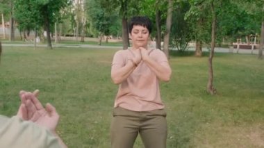 Park 'ta dört yaşlıdan oluşan orta yaşlı bayan Tai Chi Chuan antrenör eğitim grubunun arka planı.