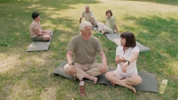 在室外瑜伽课上 漂亮的白种人男人和女人一边看手腕上漂亮的屏幕 一边休息的全景照片 — 图库视频影像