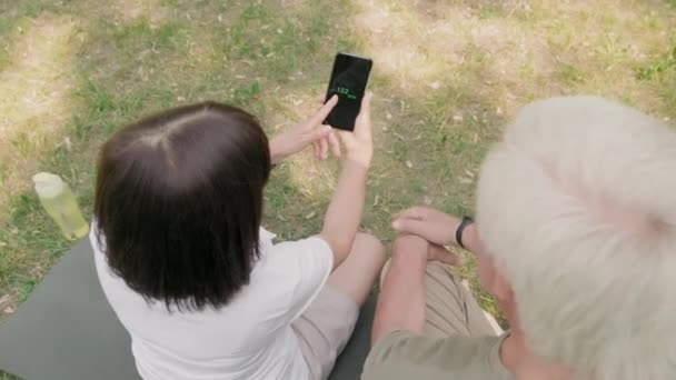 Visão Traseira Mulher Idosa Com Smartphone Nas Mãos Seu Marido — Vídeo de Stock