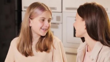 Gülümseyen anne ve kızın kendi kendine buzlu dondurmaları fındık ve meyveyle dekore ederken orta ölçekli görüntüsü.
