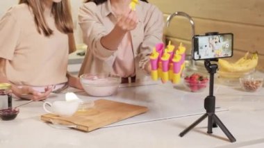 Neşeli anne ve kız, mutfak kayıt sürecinde ev yapımı dondurma yapıyor.