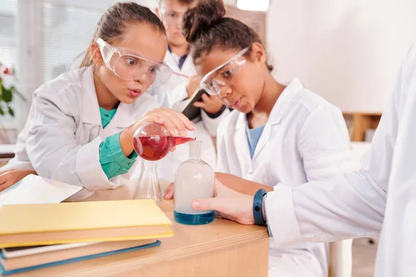 Verbazingwekkende Schoolmeisjes Beschermende Brillen Whitecoats Kijken Naar Blauwe Vloeibare Stof — Stockfoto