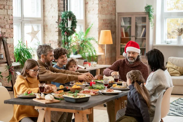 クリスマスの日にお祝いのテーブルに座り 伝統的な自家製の食べ物や飲み物を夕食に提供する幸せな多世代の家族 — ストック写真