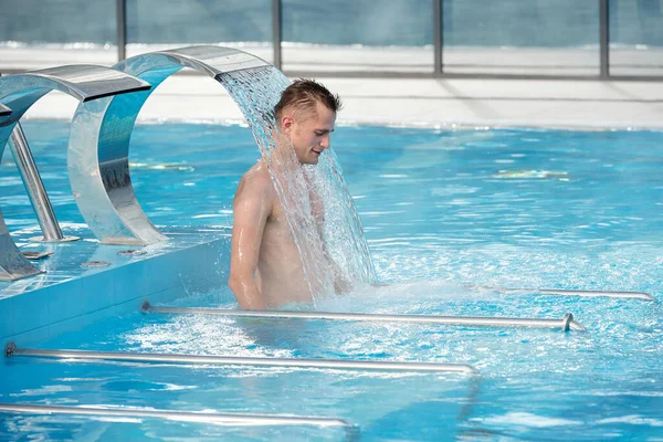 Genç Yakışıklı Adam Dinlendirici Spa Şelalesinde Duruyor Mavi Saydam Yüzme — Stok fotoğraf
