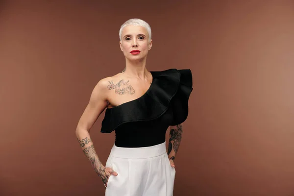 Elegant Blond Kvinna Svart Tanktop Och Vita Byxor Med Tatueringar — Stockfoto