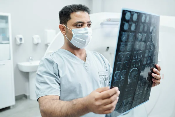 Poważny Radiolog Masce Mundurze Patrząc Zdjęcie Rentgenowskie Pacjenta Analizując Pod — Zdjęcie stockowe