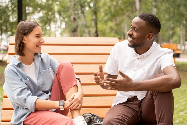 Glada Unga Interkulturella Par Casualwear Sitter Träbänk Parken Eller Torget — Stockfoto