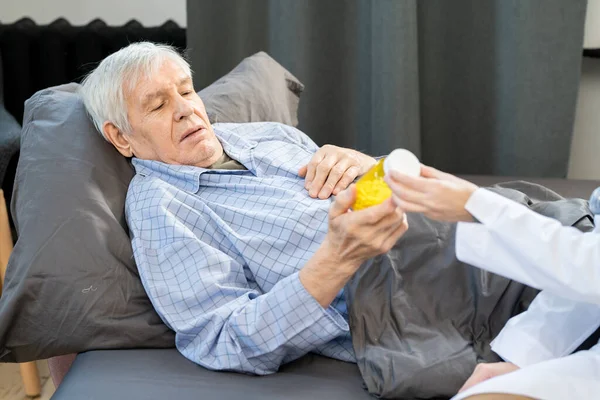 年老体衰的男人看着年轻女医生开的药瓶 给他开了新的有效的药方 — 图库照片