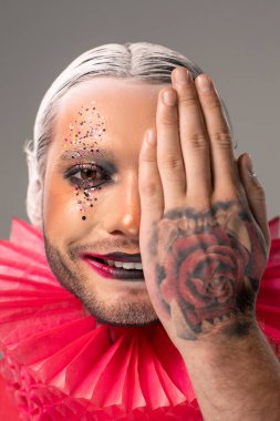 Neşeli genç bir bayan, dişlek bir gülümsemesi var. Mavi arka planda kameranın önünde dikilirken iki yarımlık taze kivi tutuyor.