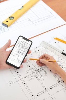 Detayları düzeltmek ya da kontrol etmek için akıllı telefon kullanan modern profesyonel mühendis ya da mimarın elleri