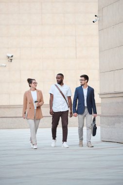 Kültürler arası üç genç yönetici bu akşam için planlarından bahsederken aynı zamanda büyük, çağdaş binalar boyunca ilerliyorlar.