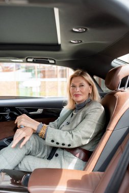 Şirin iş kadını, restorandaki ortağıyla olan önemli toplantısına giderken taksinin arka koltuğunda otururken gülümseyerek sana bakıyor.