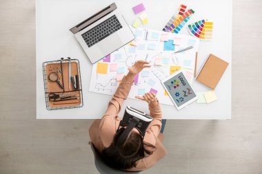 VR kulaklık hazırlama sunumuna sahip iş kadınının en üst görünümü ana hedefleri ve çalışma noktalarını içeren belgeyle birlikte masada otururken