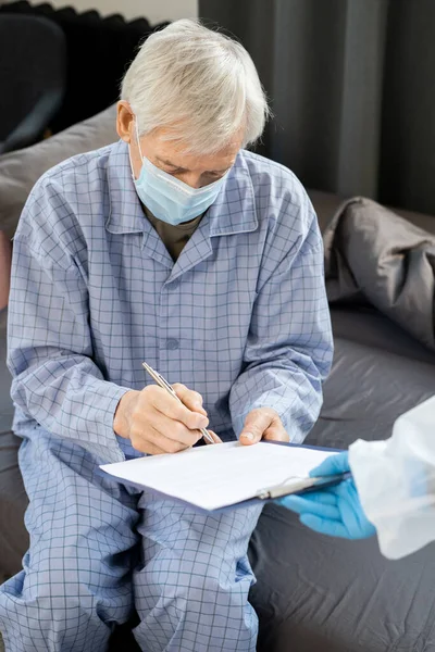 Sjuk Äldre Manlig Patient Blå Pyjamas Och Medicinsk Mask Signering — Stockfoto