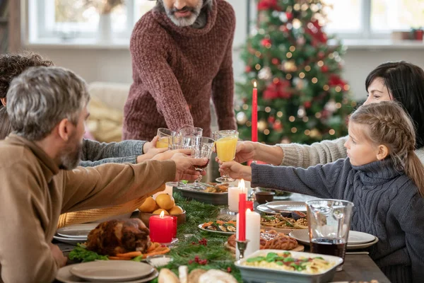 两对情侣和可爱的女孩在节日桌上用橙汁和传统的圣诞自制食品叮当作响 — 图库照片