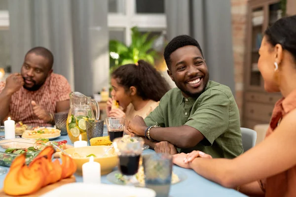 快乐的年轻非洲男人看着他可爱的姐姐或女朋友 在圣诞节或感恩节晚餐期间与她在餐桌旁聊天 — 图库照片