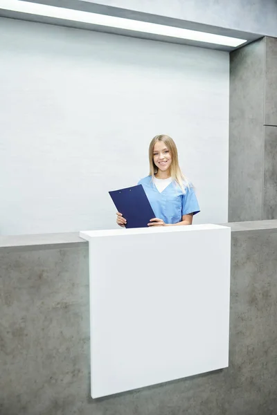 Jovem Assistente Recepcionista Loira Feliz Uniforme Azul Segurando Prancheta Com — Fotografia de Stock