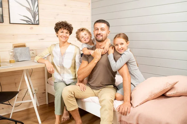 Jovem Família Feliz Quatro Sentado Cama Frente Câmera Enquanto Duas — Fotografia de Stock